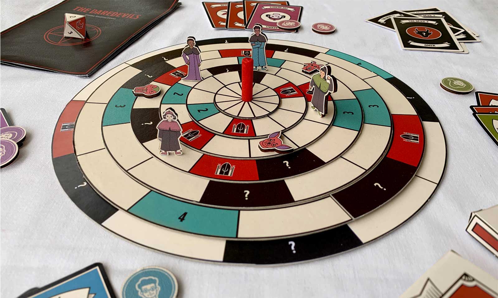 Close up of game setup. Character pieces are placed on seven circular turning boards, surrounded by game cards and tokens.